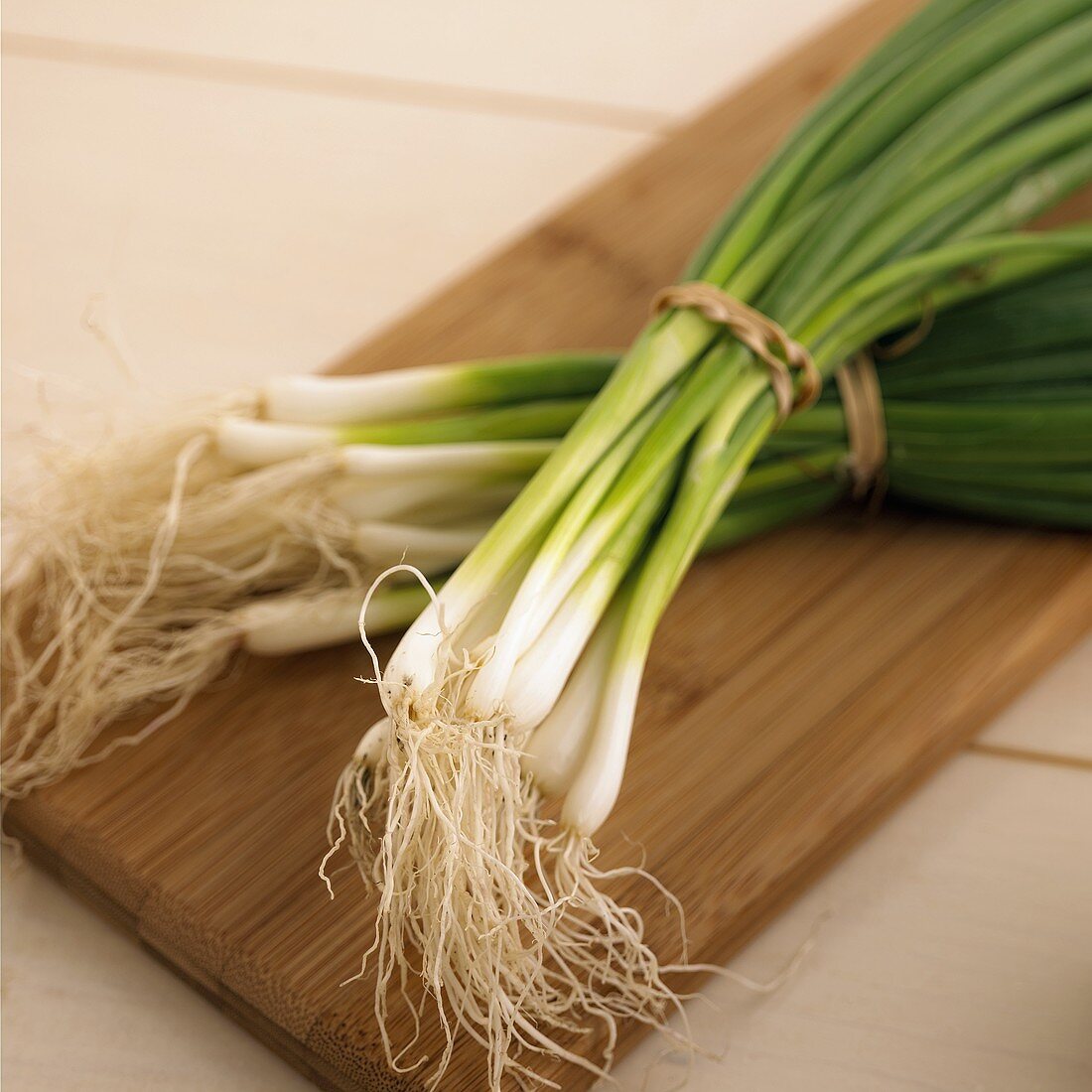 Two bunches of spring onions on chopping board