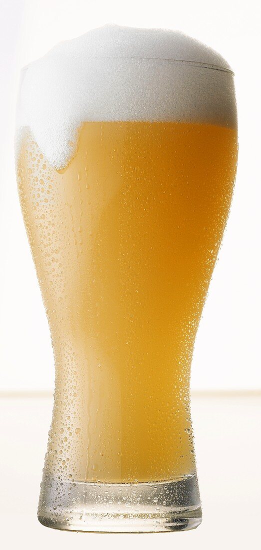 Glass of Wheat Beer Spilling Over, White Background