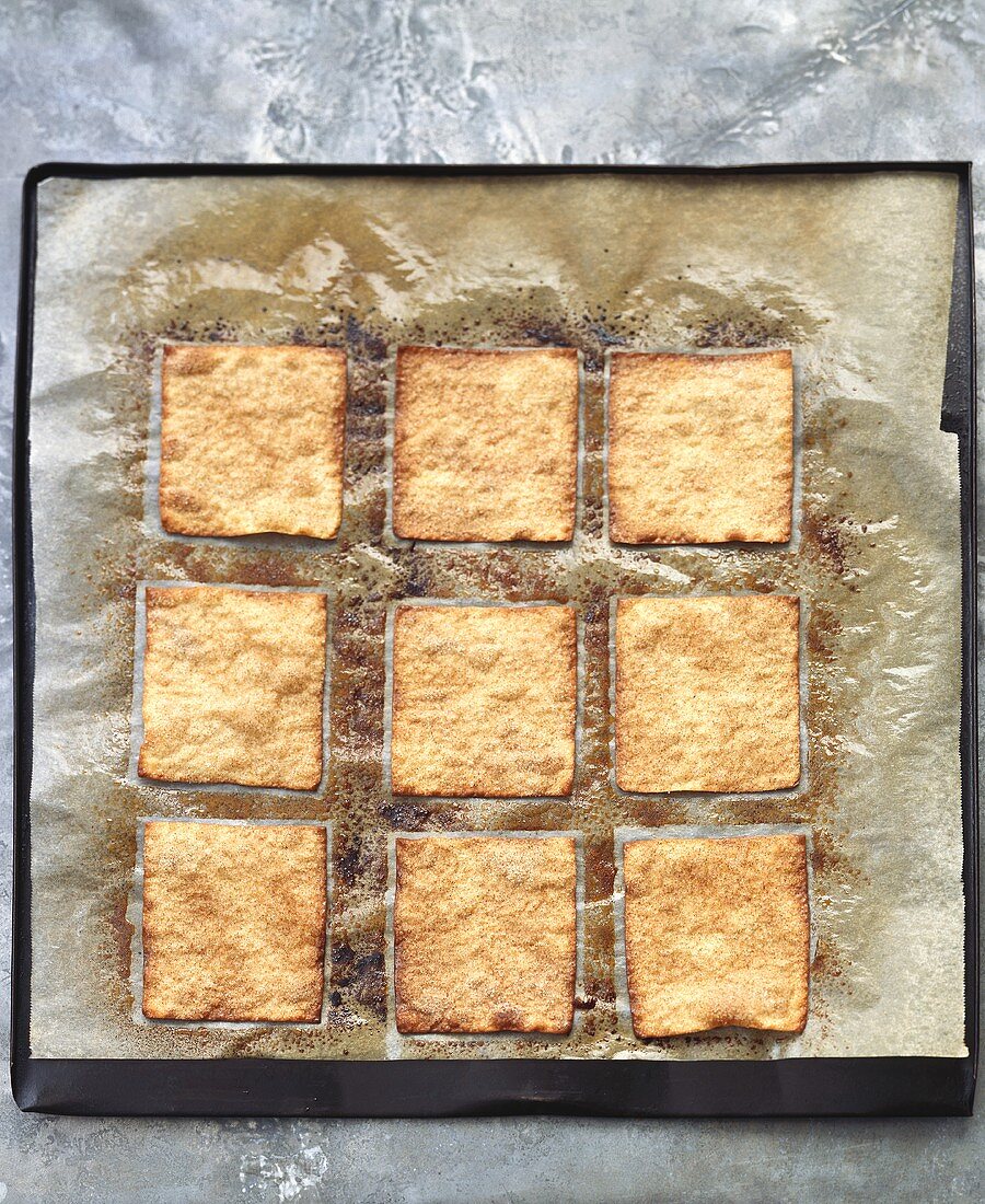 Caramelised pastry squares on baking parchment