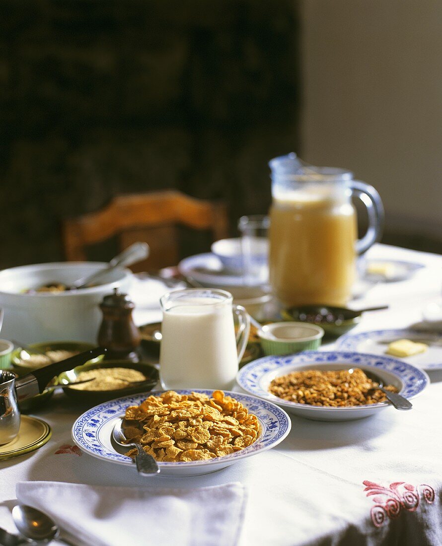 Breakfast table with cornflakes, milk and fruit juice