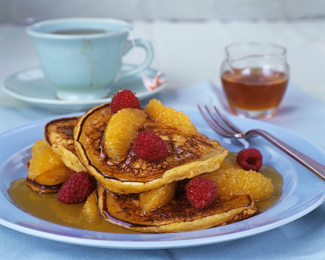 Pancakes with honey, orange segments and raspberries
