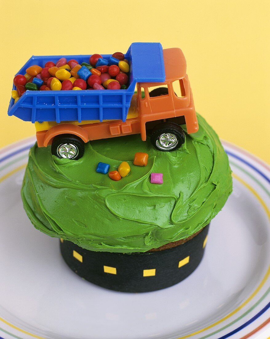 Toy wagon full of sweets on cup-cake with green cream