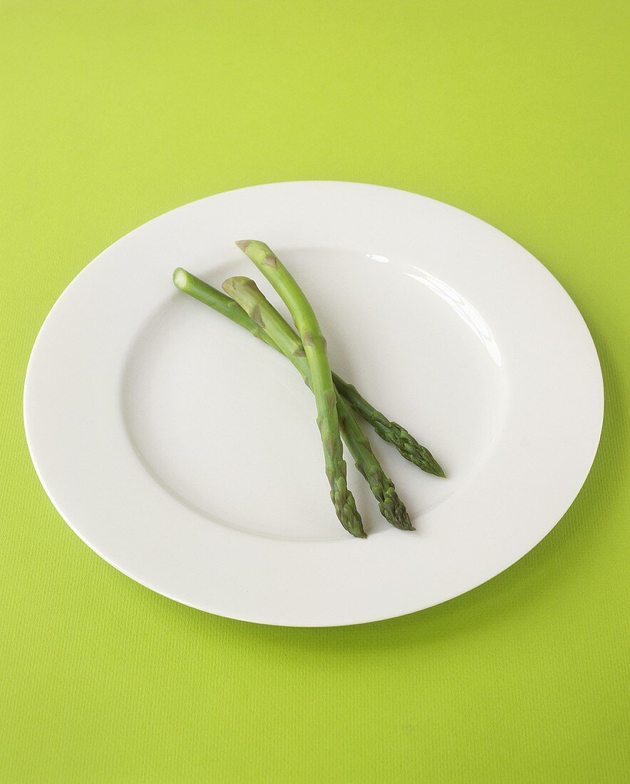 Three spears of green asparagus on white plate