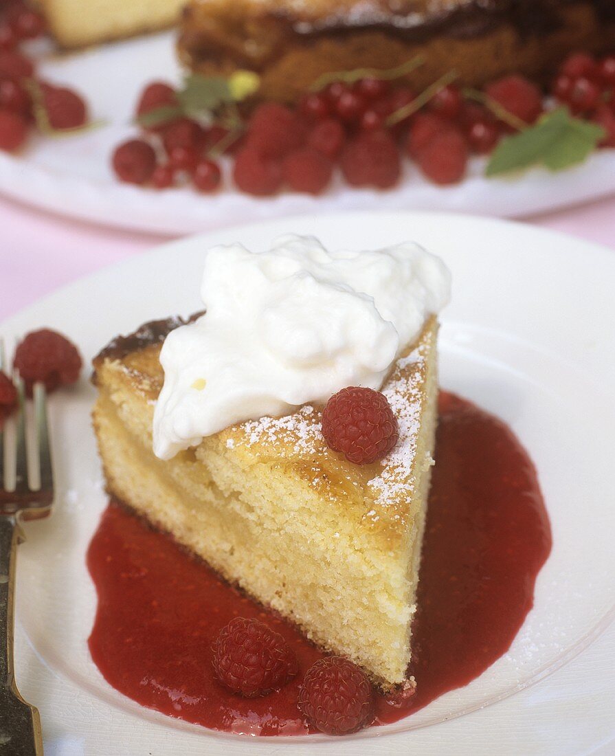 A piece of cake with raspberry sauce and cream