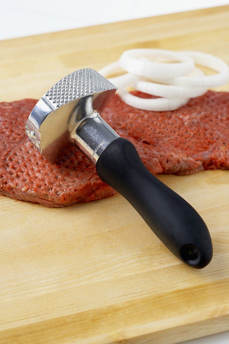 Meat Tenderizer on Pounded Steak with Onion Slices