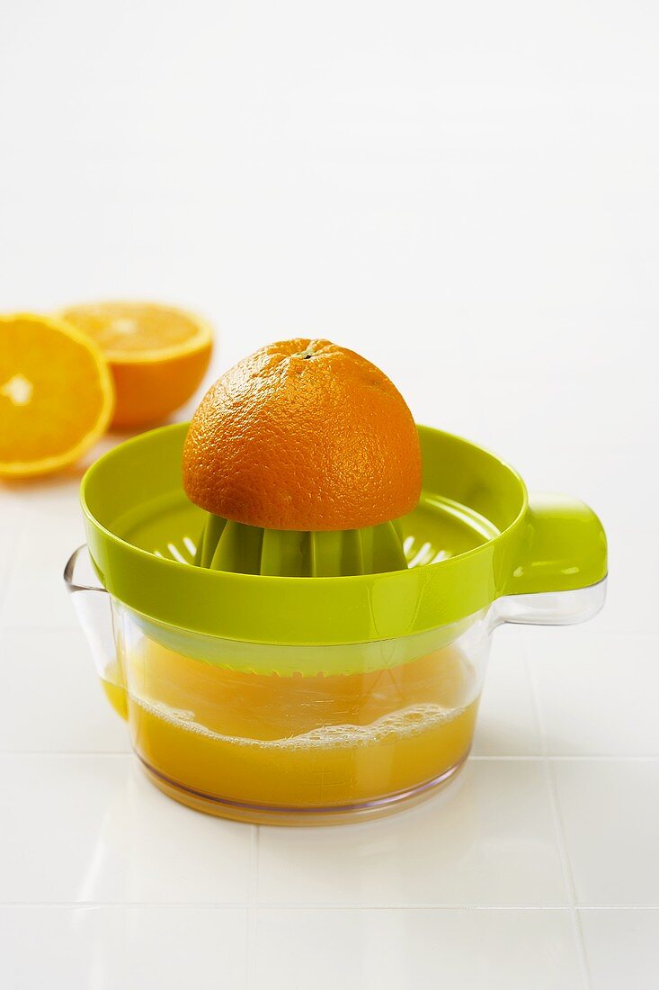 Orange Half on a Juicer, Freshly Squeezed Orange Juice in Juicer Pitcher