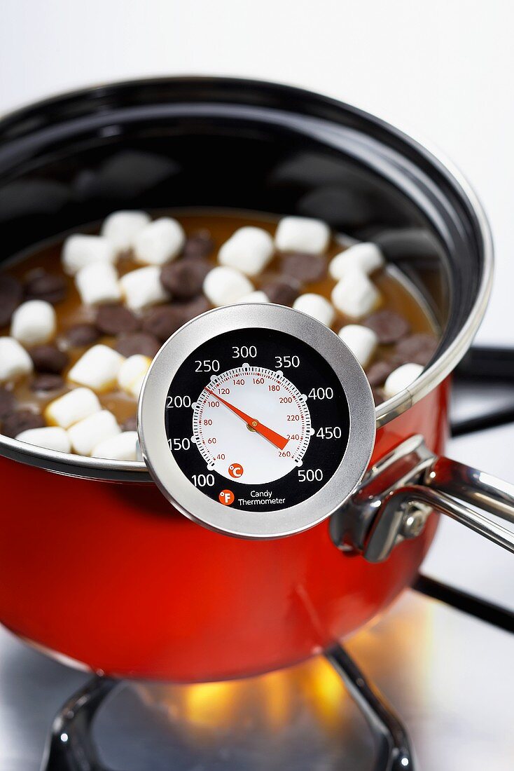 Thermometer auf Kochtopf mit Schokolade und Marshmallows