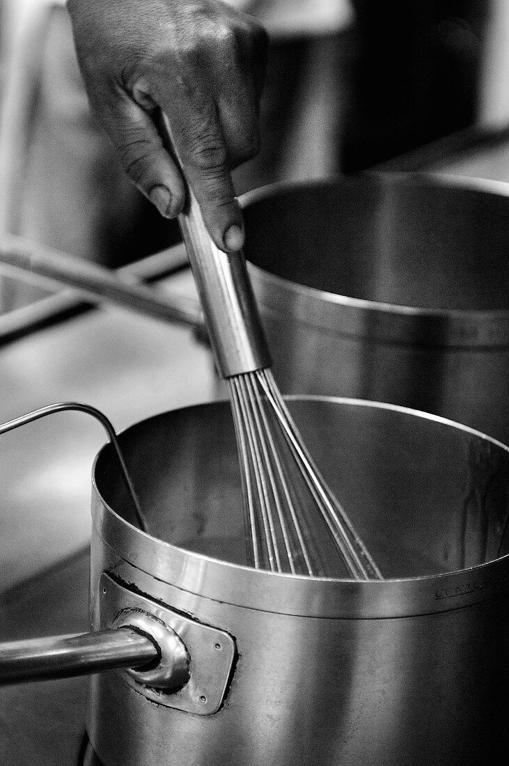 A Hand Using a Whisk in a Saucepan