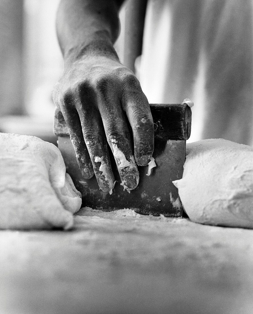 A Hand Using a Scraper with Dough