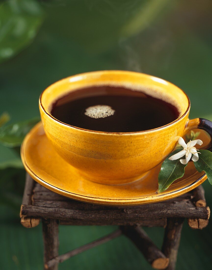 Dampfender schwarzer Kaffee in gelber Tasse