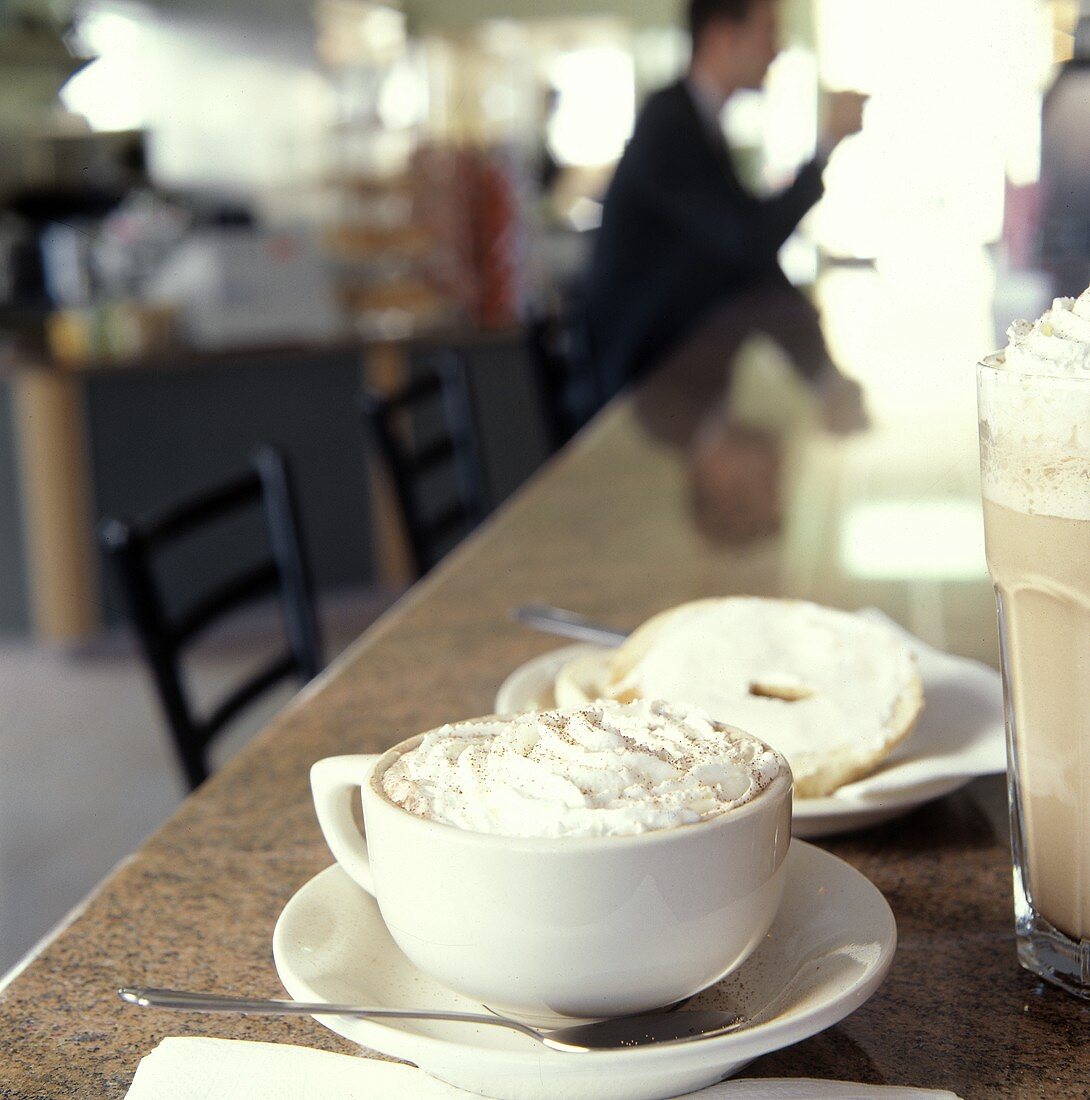 Cappuccino mit Bagel auf Theke im Coffeeshop