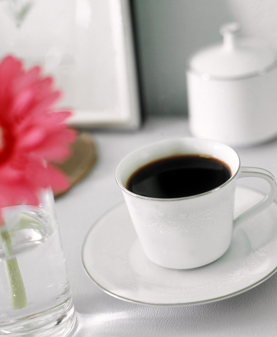 Eine Tasse Kaffee, im Hintergrund eine Zuckerdose