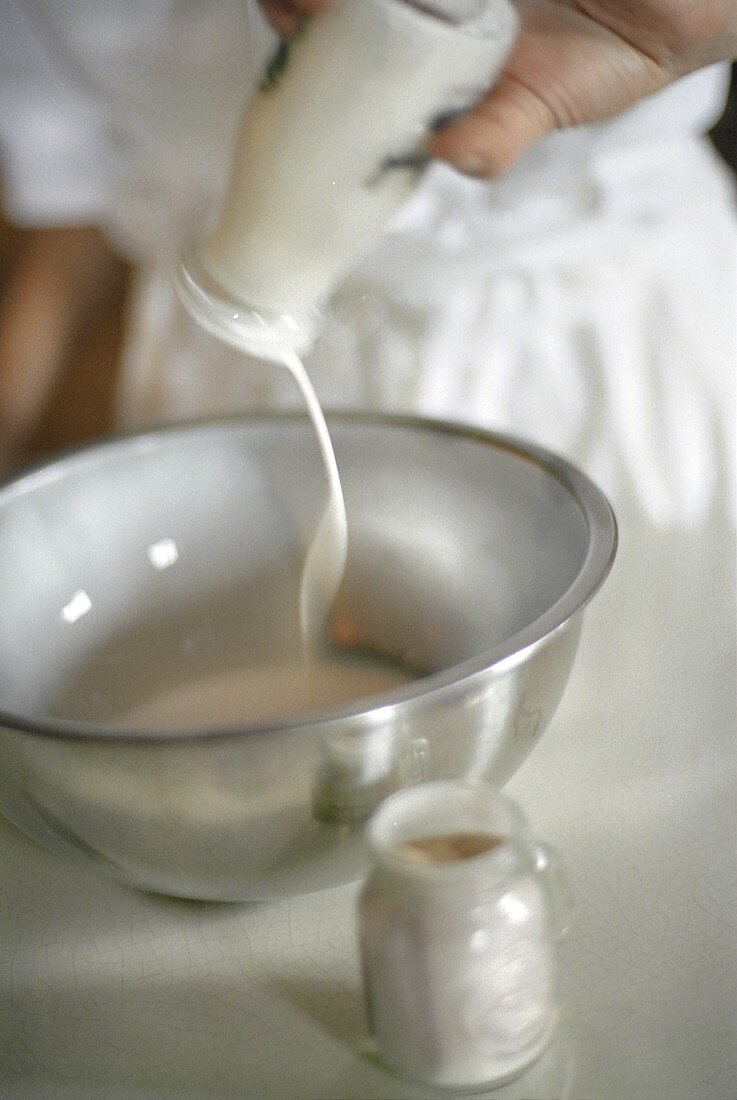 Milch aus der Flasche in eine Schüssel gießen