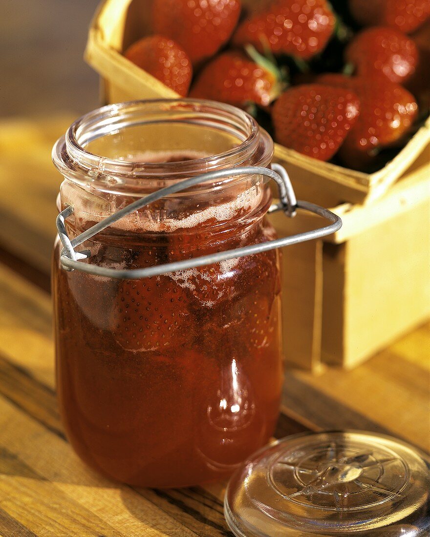 Erdbeermarmelade im Glas vor frischen Erdbeeren
