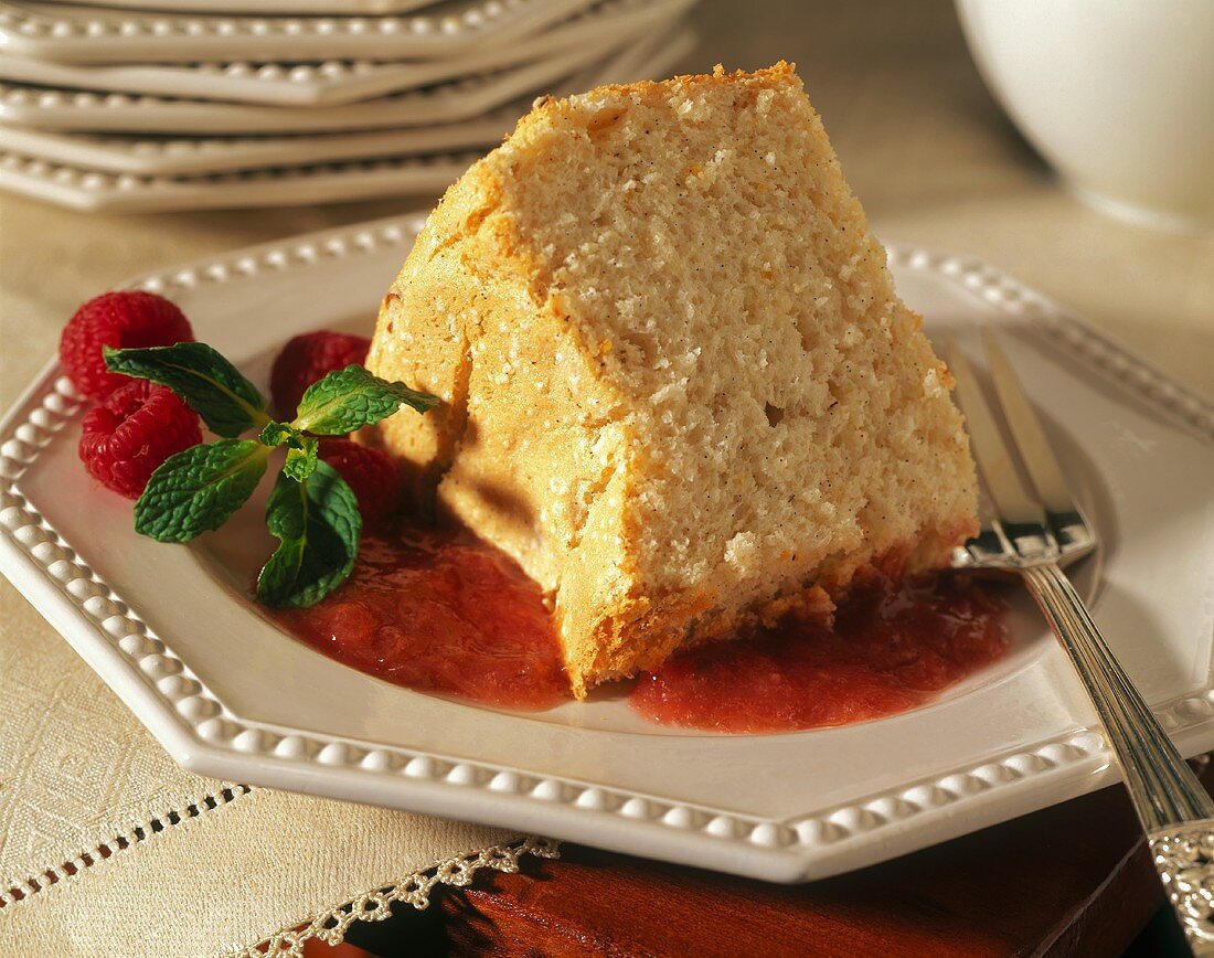 Ein Stück Mohn-Biskuitkuchen auf Himbeer-Rhabarber-Sauce