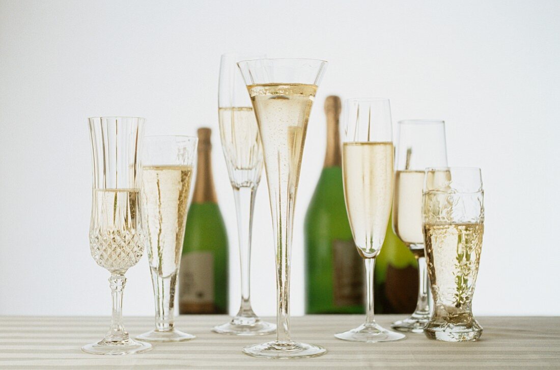Champagne in a Variety of Glasses; Bottles of Champagne in the Background