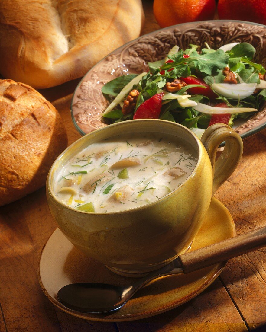 Kartoffel-Lauchsuppe in Tasse, im Hintergrund gemischter Salat