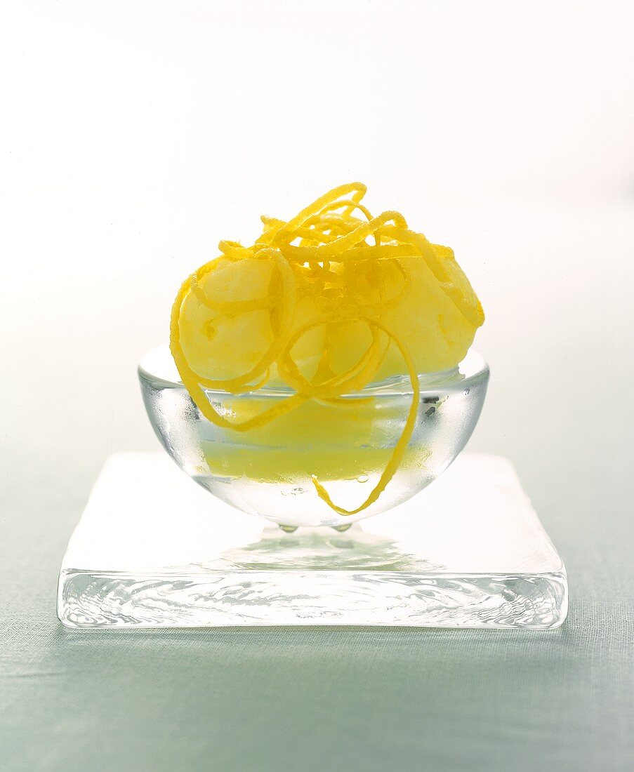 Scoops of Lemon Sorbet with Lemon Zest in a Glass Bowl; Resting on Square Glass