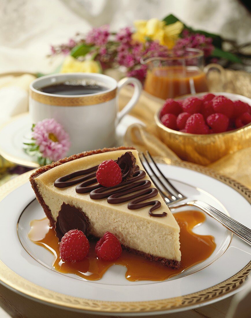 Stück Käsekuchen mit Karamellsauce und frischen Himbeeren