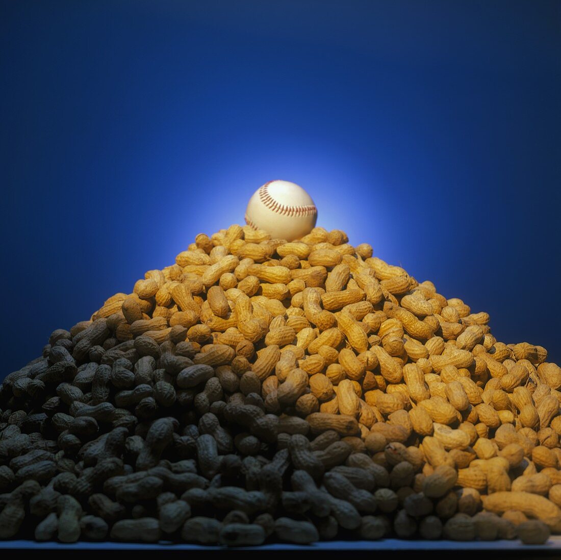 Pile of Unshelled Peanuts with a Baseball Resting on Top