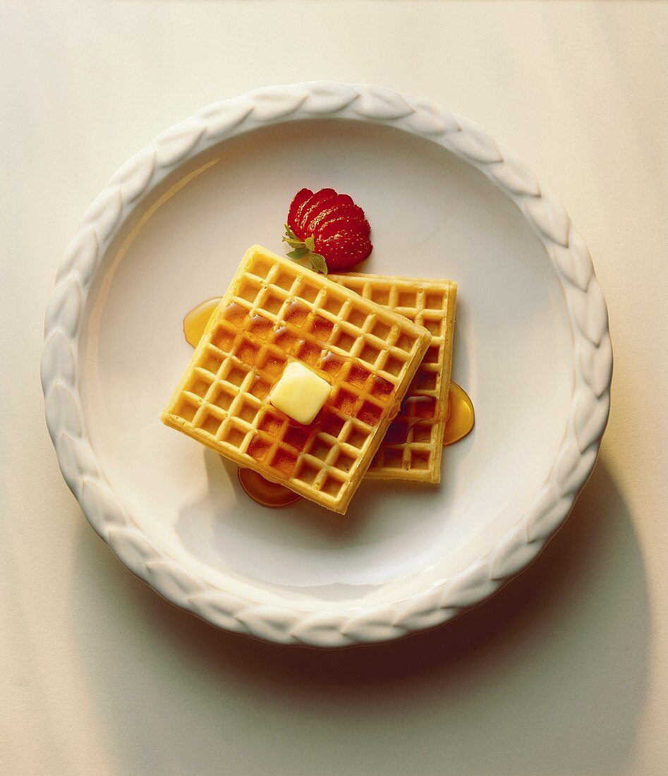 Two Waffles on a White Plate; Syrup and Butter