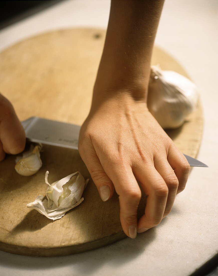 Knoblauch kleinschneiden und mit Messer zerdrücken