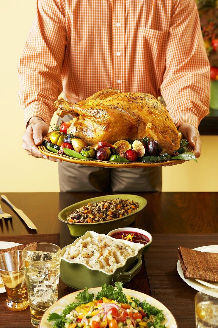 Mann serviert Platte mit gebratenem Turkey zu Thanksgiving