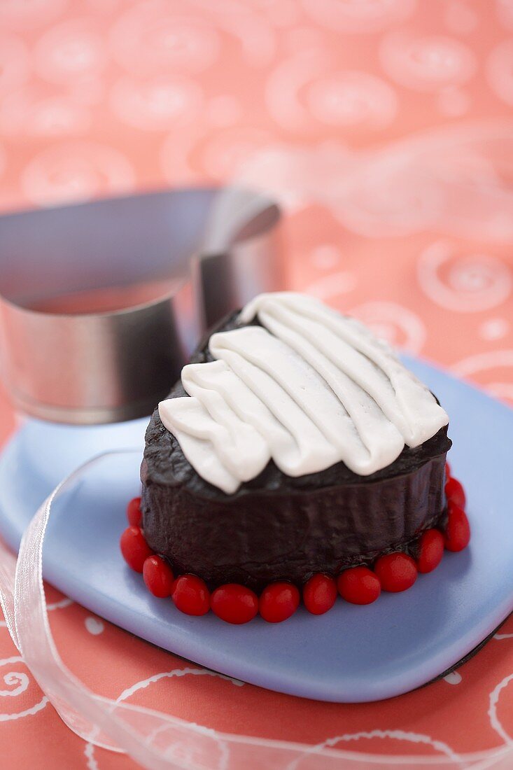 Cupcake mit Schokoladen-Vanille-Glasur und roten Schokolinsen