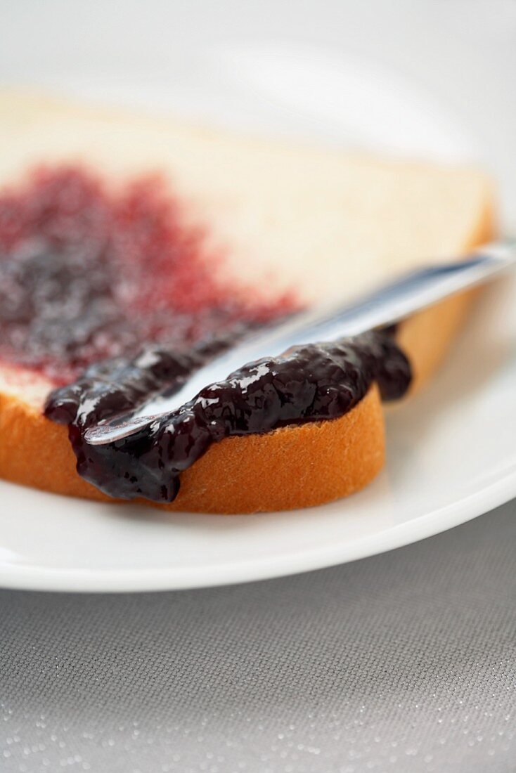 spreading grape jelly on bread