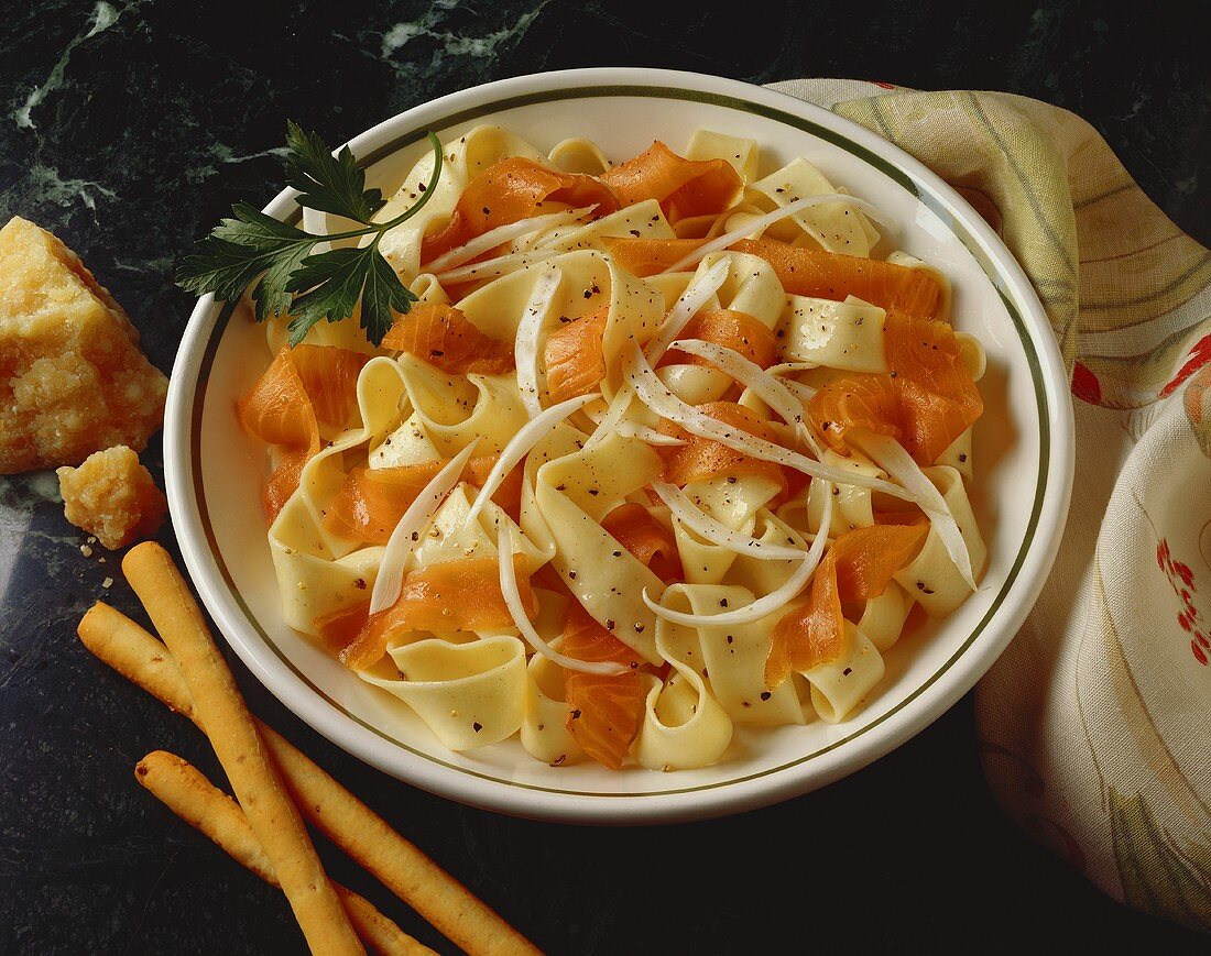 Bandnudeln mit Lachs, daneben Grissini und Parmesan