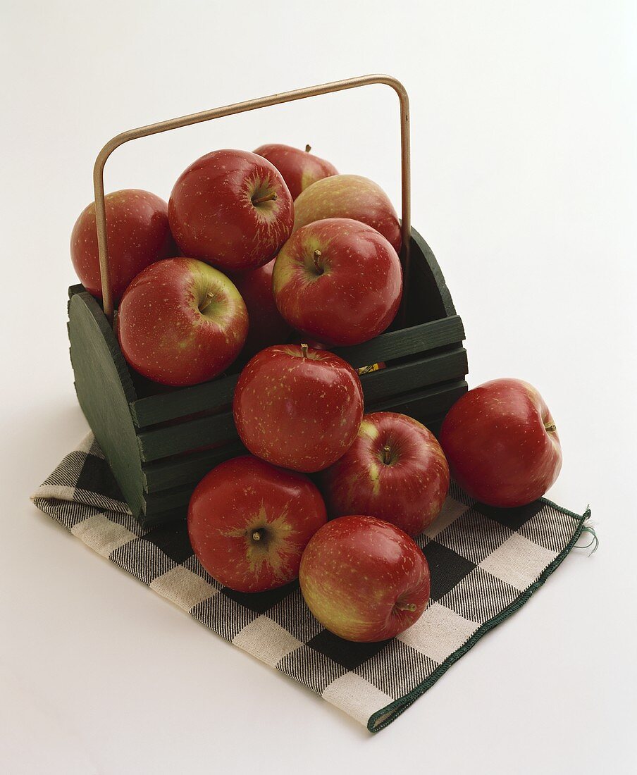 Rote Äpfel im Holzkorb und auf kariertem Tuch