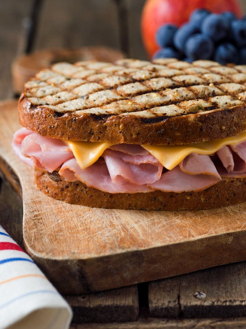 Whole Grilled Ham and Cheese Sandwich on a Cutting Board