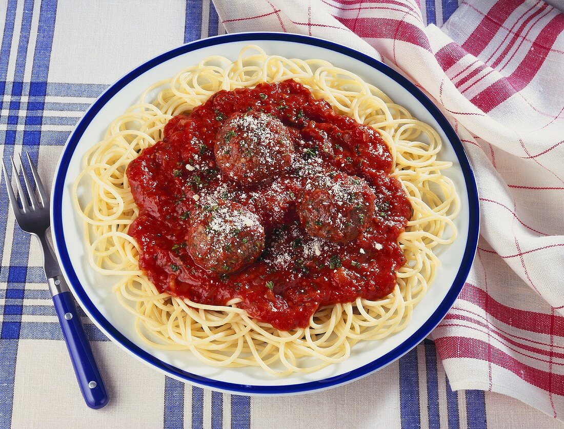 Plate of Spaghetti and Meatballs on Blue and White Table Cloth; Fork