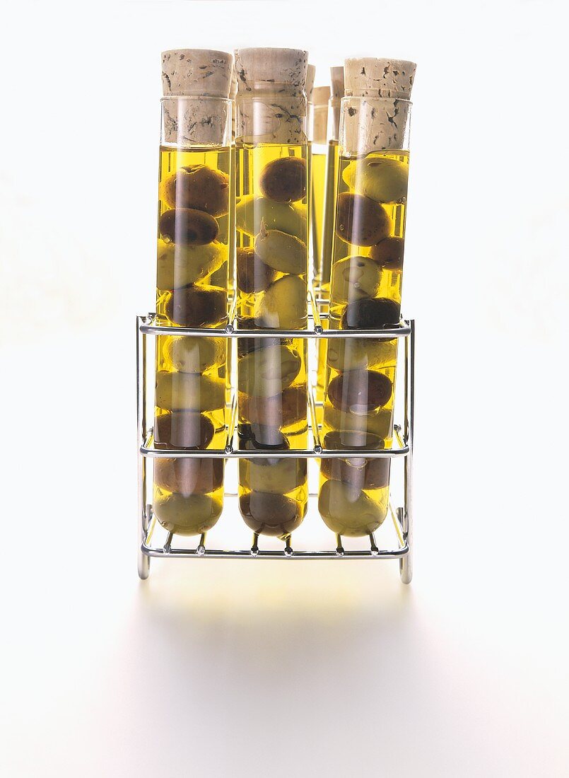 Assorted Olives in Oil in Test Tubes on Storage Rack; White Background