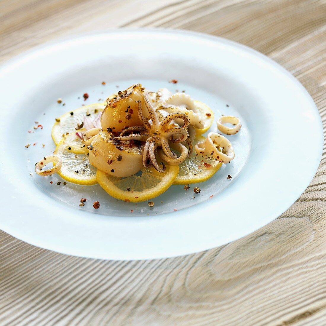 Scallops and Squid Over Lemon Slices on a Plate