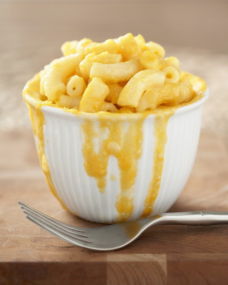 Bowl of Macaroni and Cheese with Cheese Sauce Dripping Down Side of Bowl