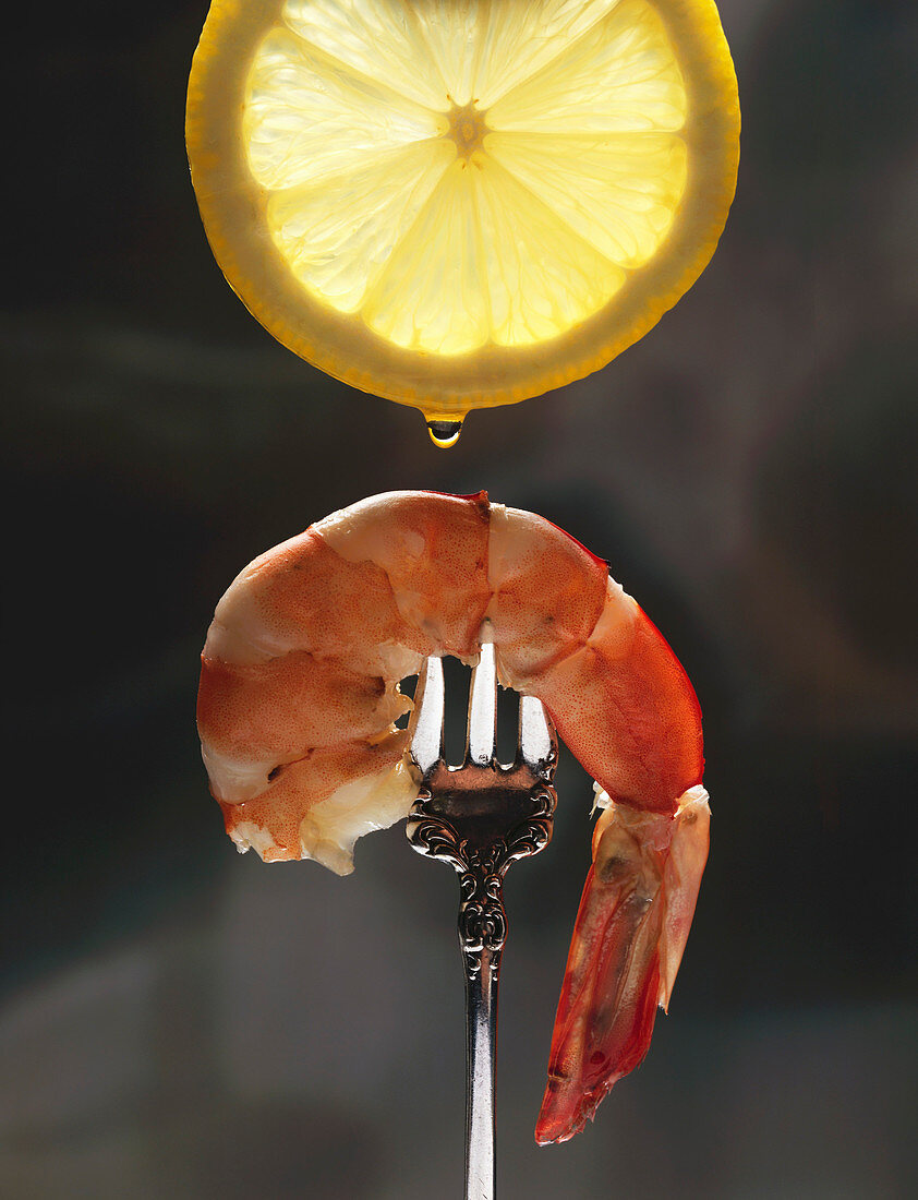 A Drop of Lemon Juice Falling from a Lemon Slice onto a Piece of Shrimp