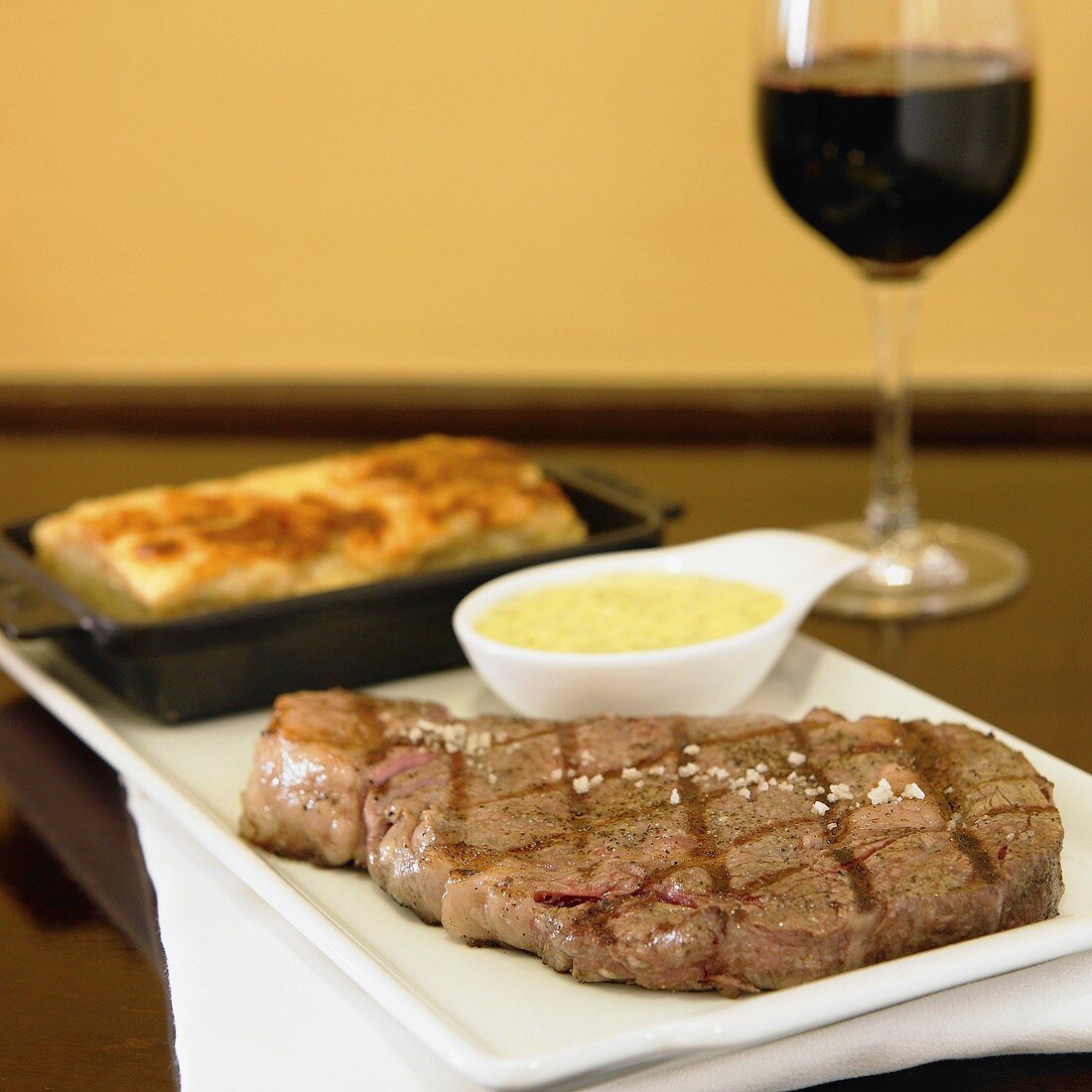 Gegrilltes Rindersteak mit Kartoffelgratin und Glas Rotwein