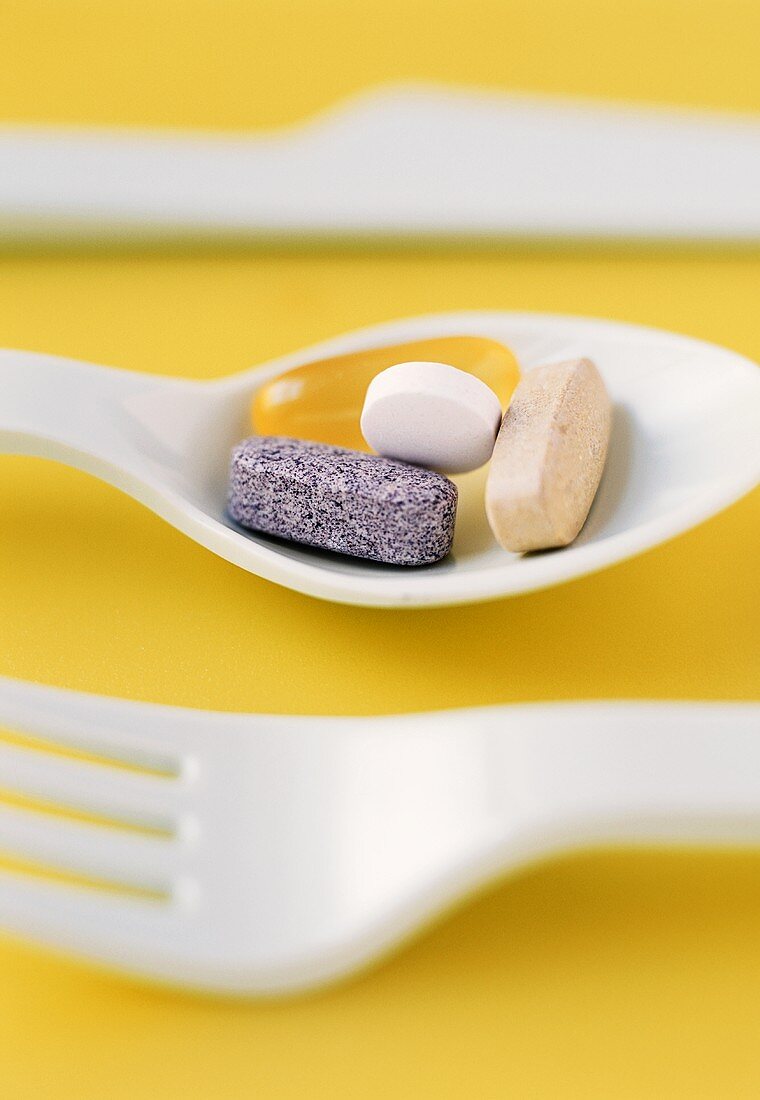 Assorted Vitamins on a Plastic Spoon; Plastic Fork