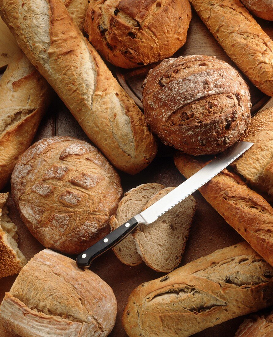 Many Assorted Loaves of Bread with a Bread Knife