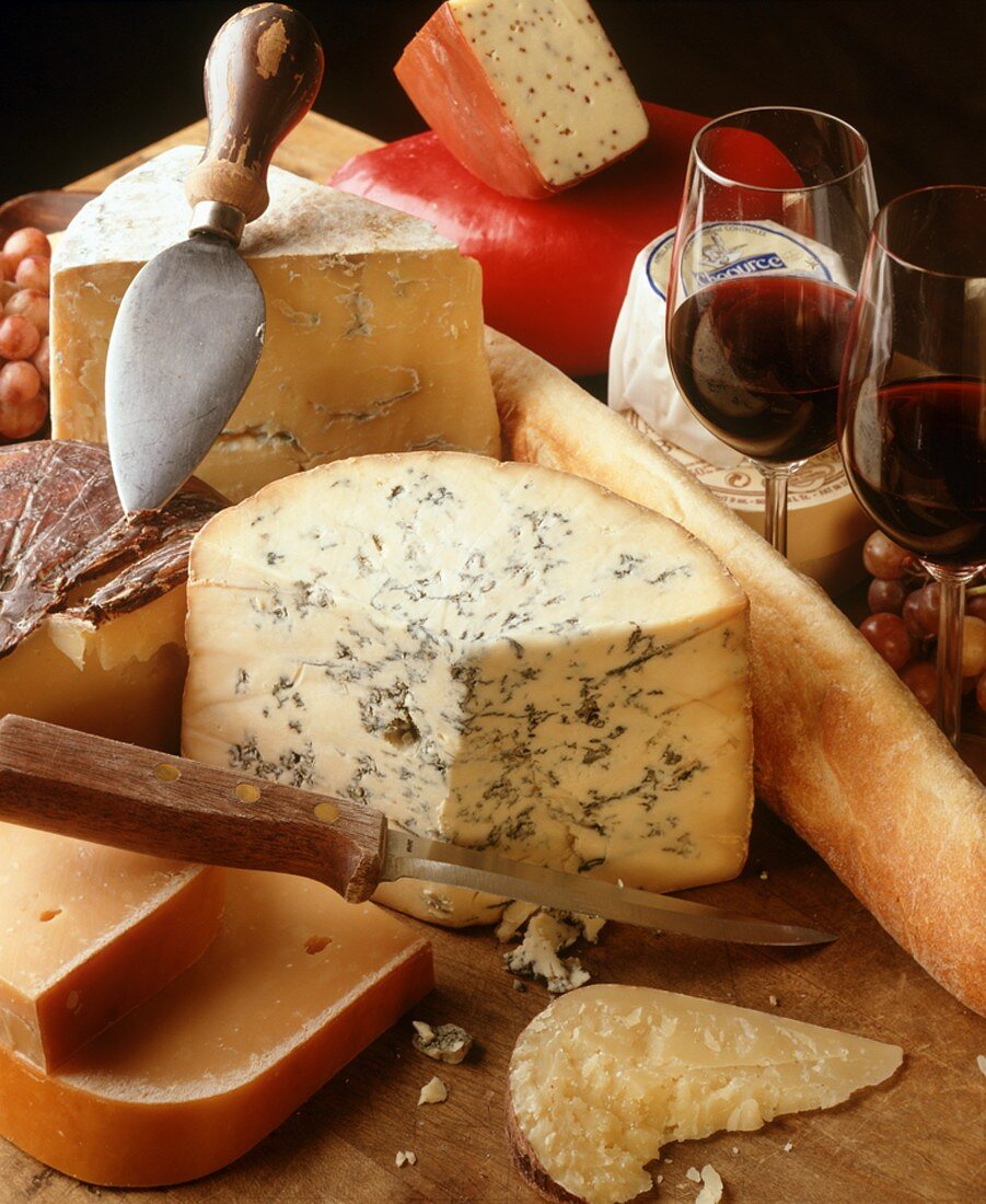 Assorted Wheels of Cheese with Glasses of Red Wine