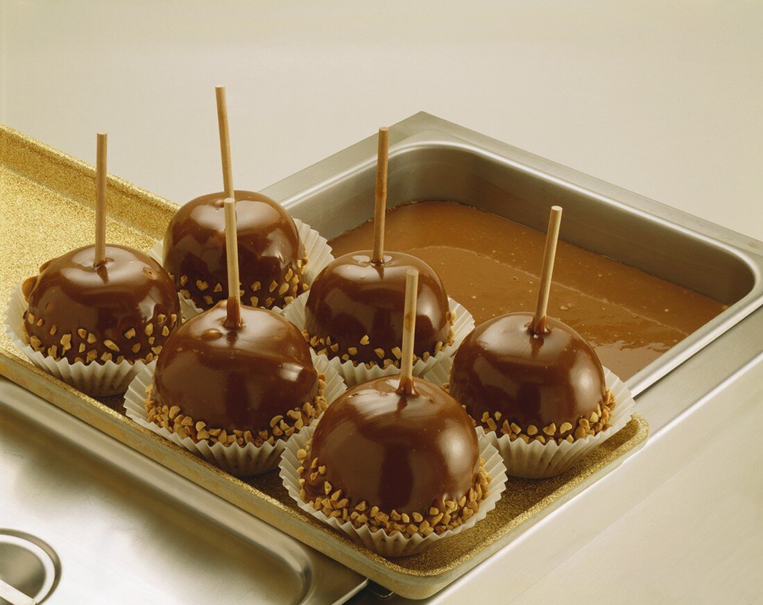 Toffee apples rolled in nuts, in paper cases