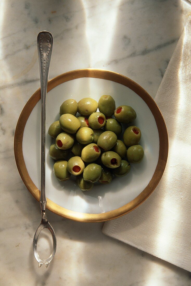 Gefüllte grüne Oliven auf Teller mit Olivenlöffel