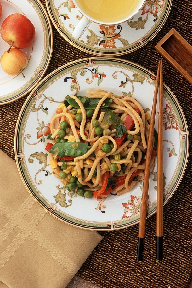 Spicy Udon Noodles with Vegetables on a Plate with Chopsticks