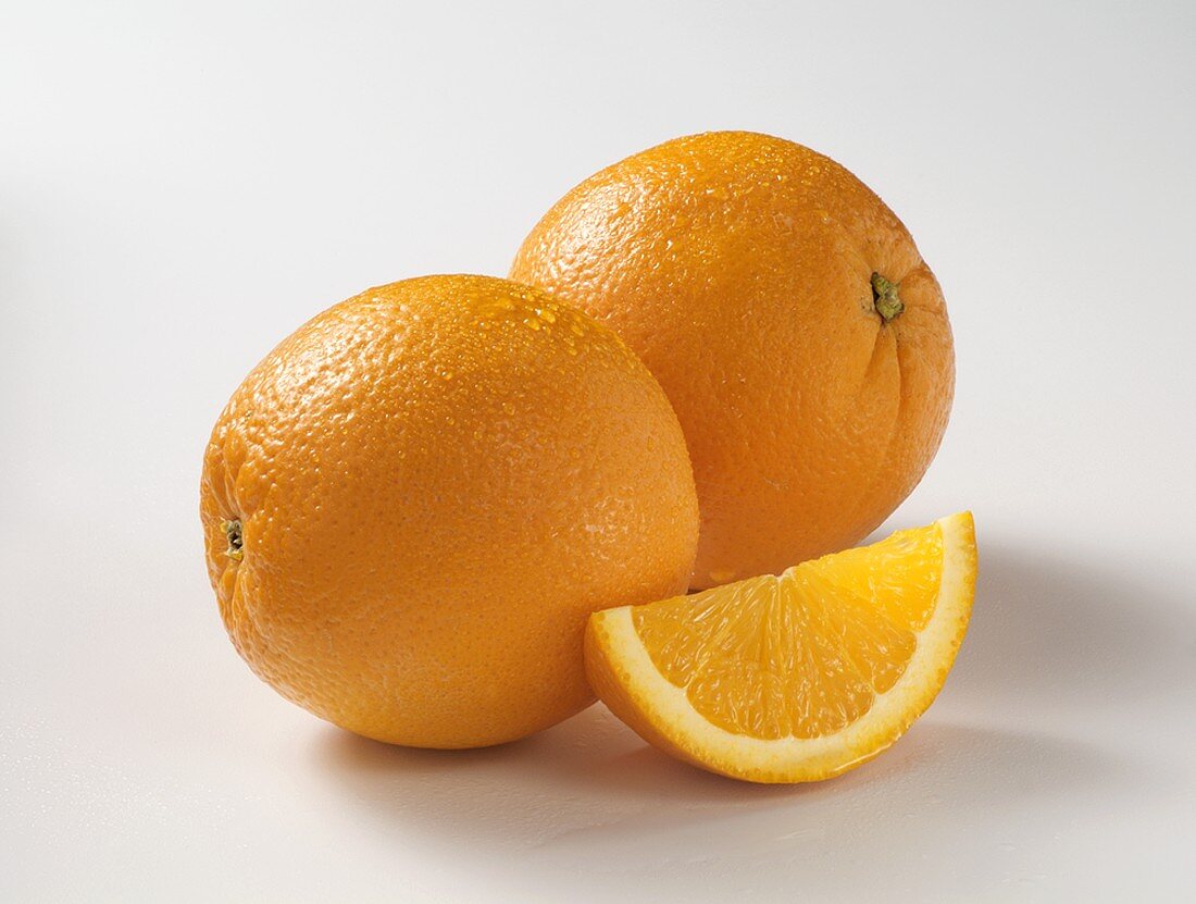 Two Whole Oranges with an Orange Wedge