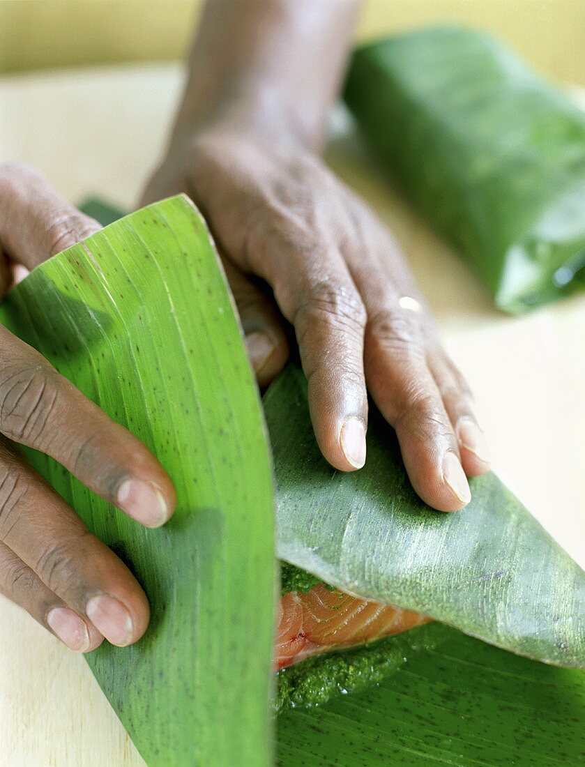 Hands Wrapping Salmon in Banana Leaves