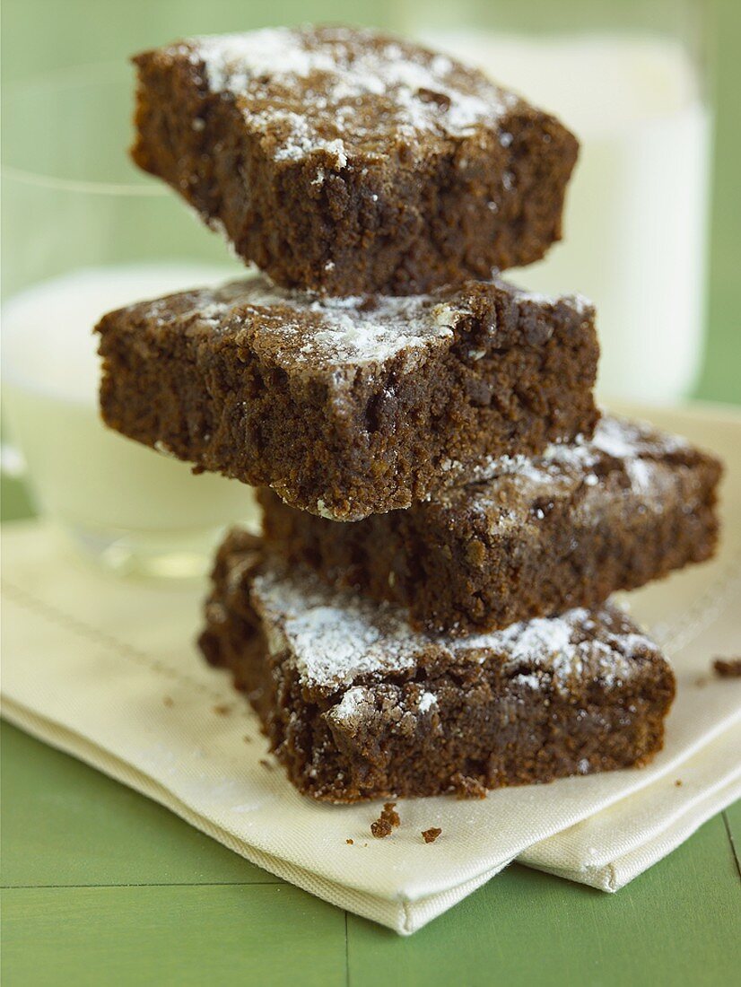 Four Brownies Stacked by a Glass of Milk