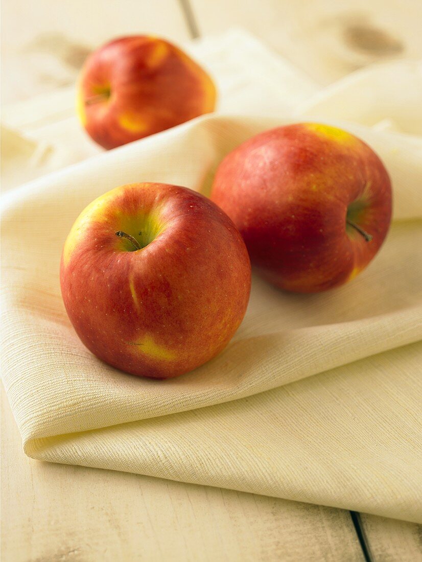 Drei ganze rote Äpfel auf Tuch