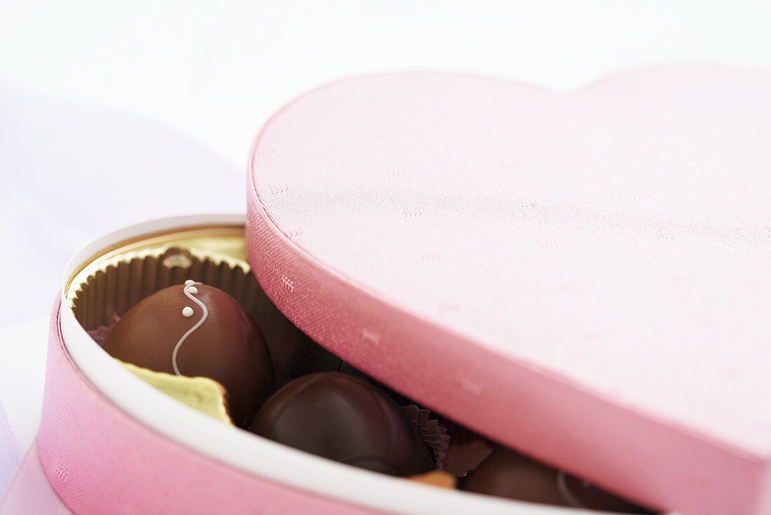 Schokoladenpralinen in herzförmiger rosa Schachtel