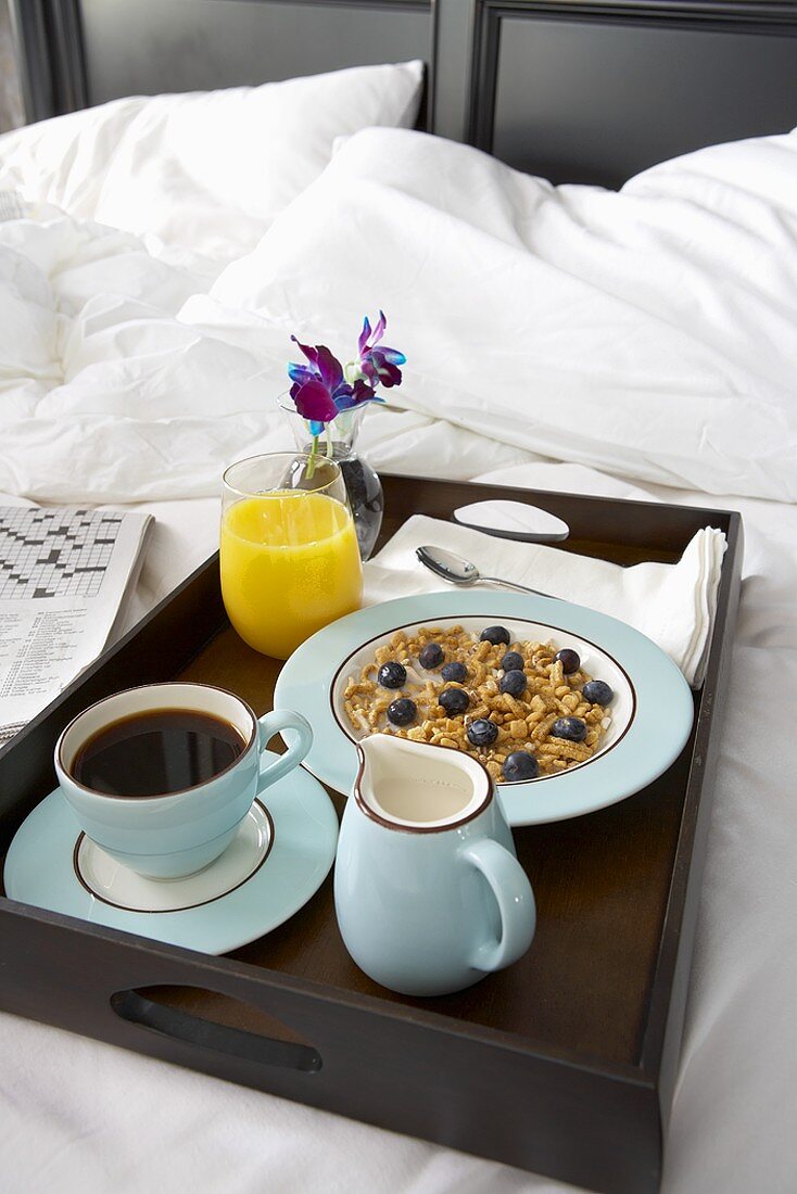 Frühstück im Bett mit Müsli, Kaffee und Orangensaft